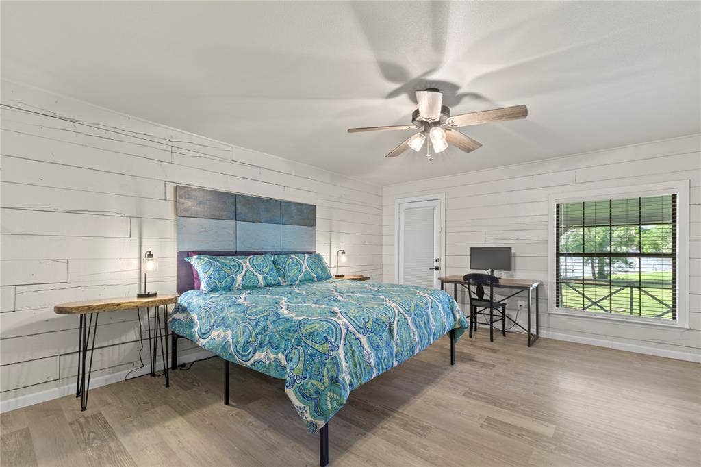 323 Dyer Circle, Payne Springs, TX 75156 Bedroom featuring wood-finish flooring, white shiplap walls, a ceiling fan with light fixture, a window with blinds, and a white interior door