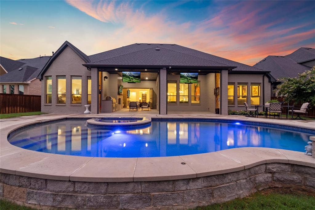 Twilight view of the pool and the back of the home.