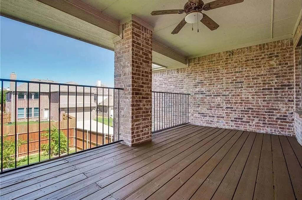 13990 Stevens Point Drive, Frisco, TX 75033 Covered outdoor balcony featuring wood-finish flooring, a brick exterior wall, black metal railing, and a ceiling fan