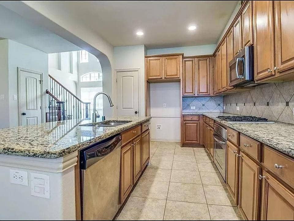 13990 Stevens Point Drive, Frisco, TX 75033 Kitchen featuring an island with granite countertops, stainless steel sink with gooseneck faucet, light wood cabinetry, and a gas cooktop