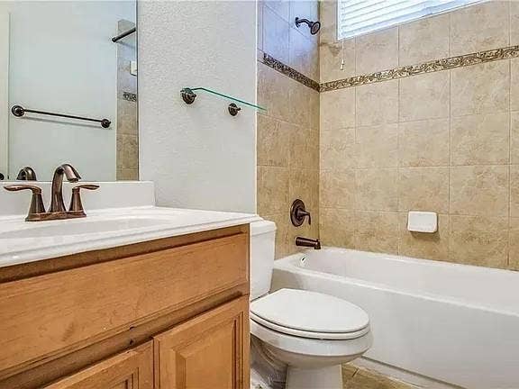 13990 Stevens Point Drive, Frisco, TX 75033 Bathroom featuring a white vanity with a bronze-finish faucet, a toilet, and a tiled shower-tub combination