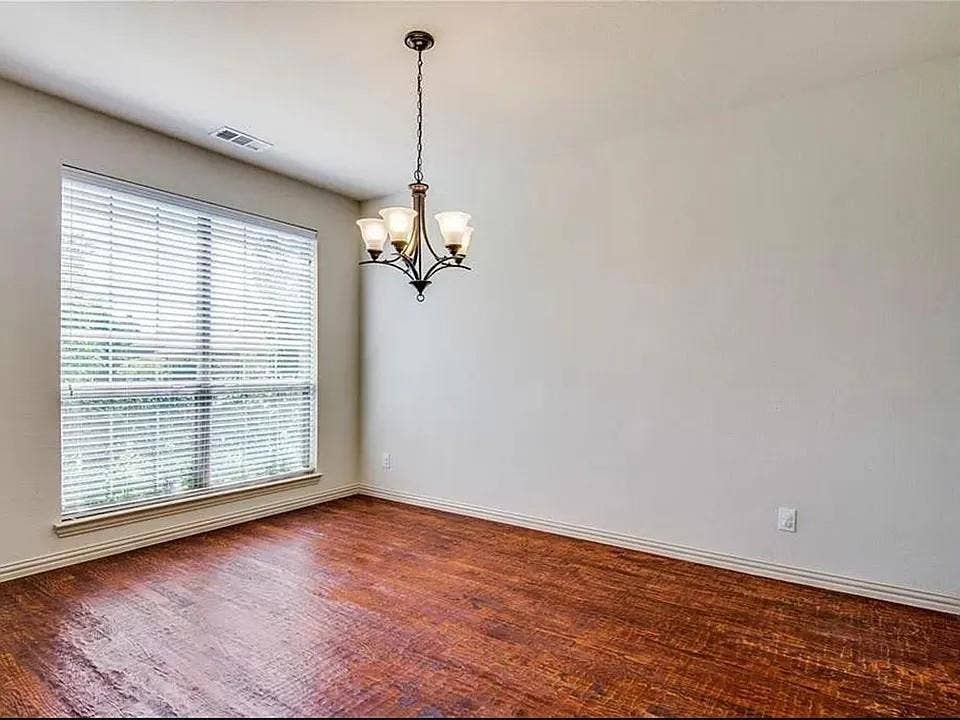 13990 Stevens Point Drive, Frisco, TX 75033 Spacious room featuring wood-finish flooring, a large window with blinds, and a multi-arm chandelier