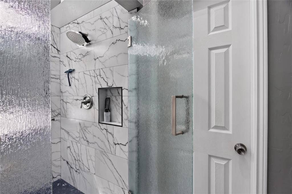 4243 Millview Lane, Dallas, TX 75287 This oversized, updated remodeled shower completed in 2026 ($9000) features Rain shower head, privacy rain affect textured glass enclosure and stunning designer tile that compliments the bathroom's sophisticated color palette.