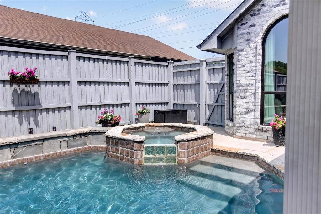 4243 Millview Lane, Dallas, TX 75287 View of sparkling pool and spa. A premium board on board fence surrounds the backyard, providing a peaceful and secluded setting to unwind or host family and friends.