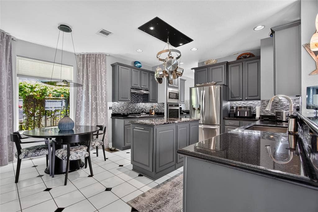 4243 Millview Lane, Dallas, TX 75287 This beautifully appointed kitchen is designed to Impress, offering an expanded center island with a hidden trash pull-out bin, grantie counter tops, abundate work space, recessed lighting, under cabinet lighting, deep SS sink with updated faucet and durable tile floors. A reinforced ceiling mounted cookware rack adds both function and character.