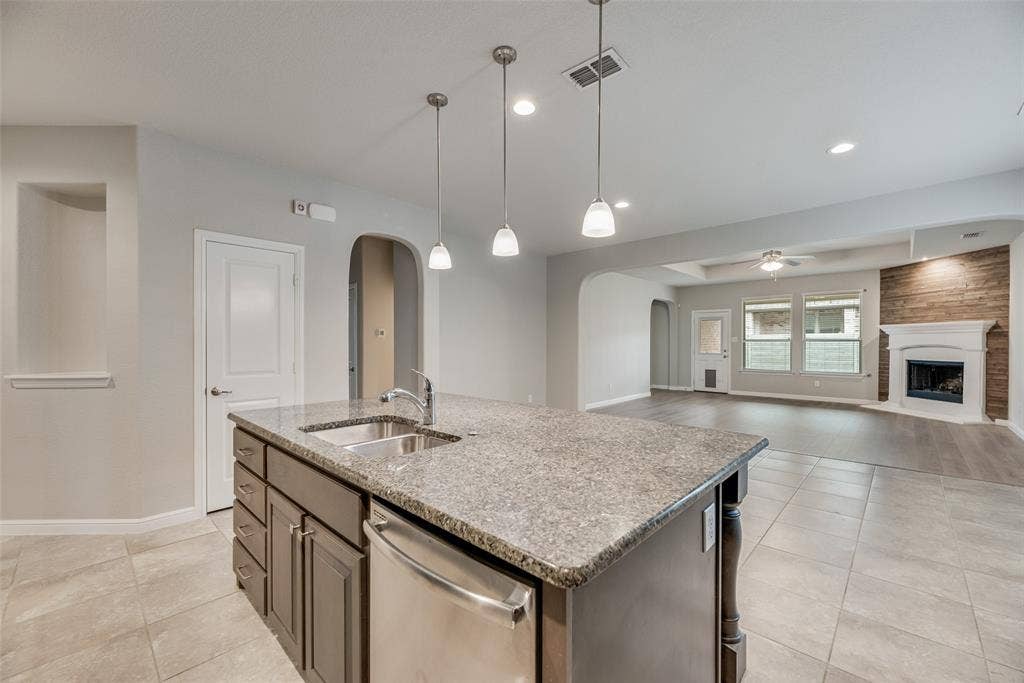 Kitchen featuring stainless steel dishwasher, arched walkways, a ceiling fan, a fireplace, and recessed lighting
