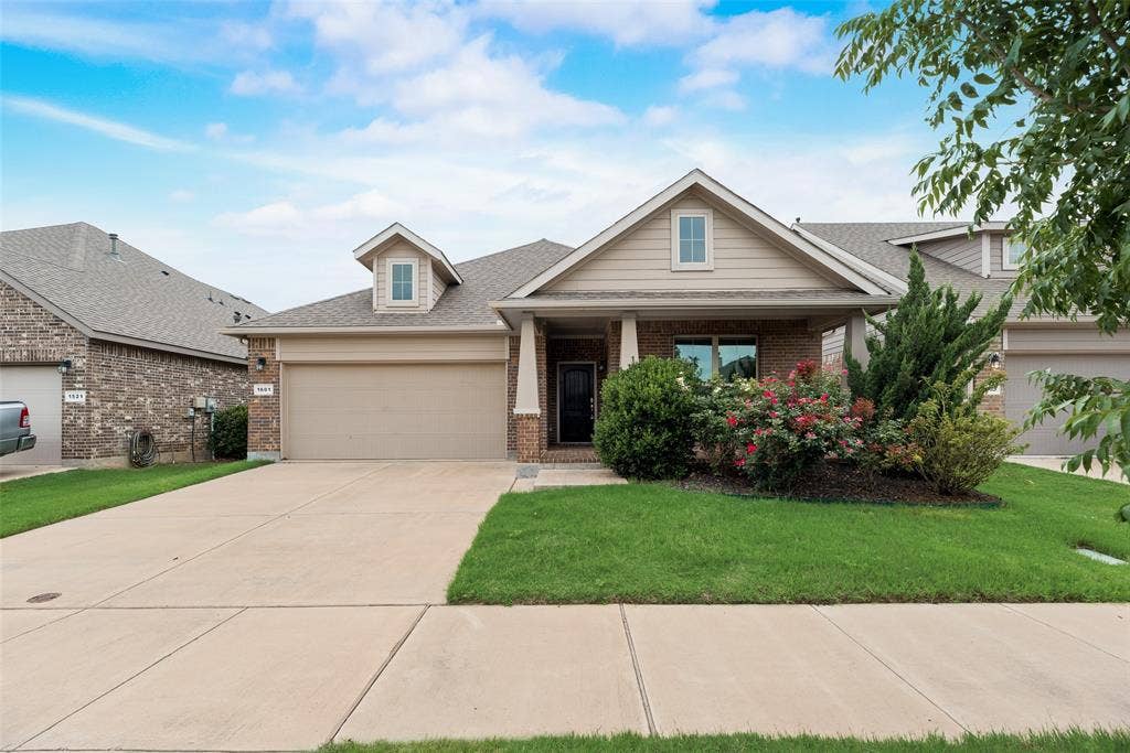 View of front facade featuring brick siding, a garage, driveway, and a front yard