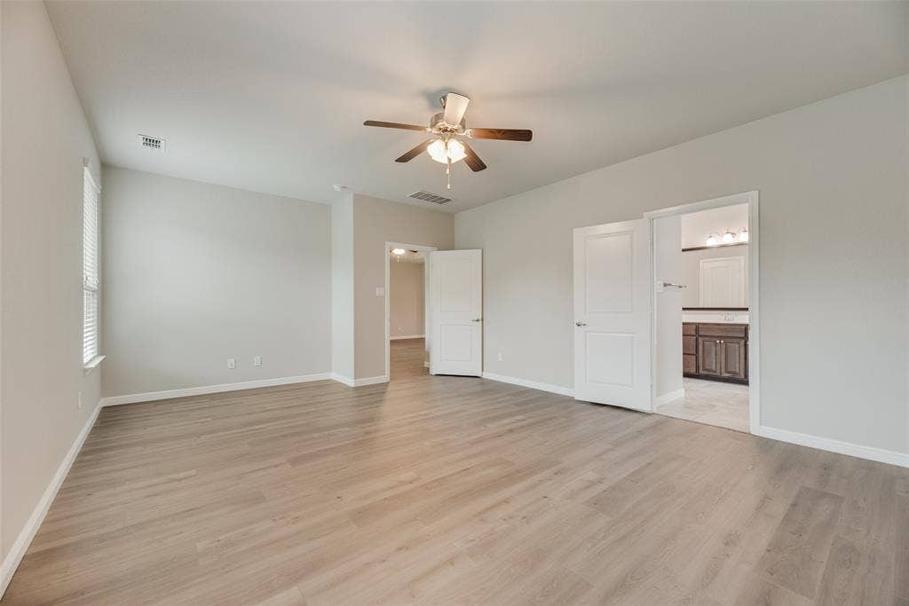 Unfurnished bedroom with light wood-type flooring, connected bathroom, and a ceiling fan