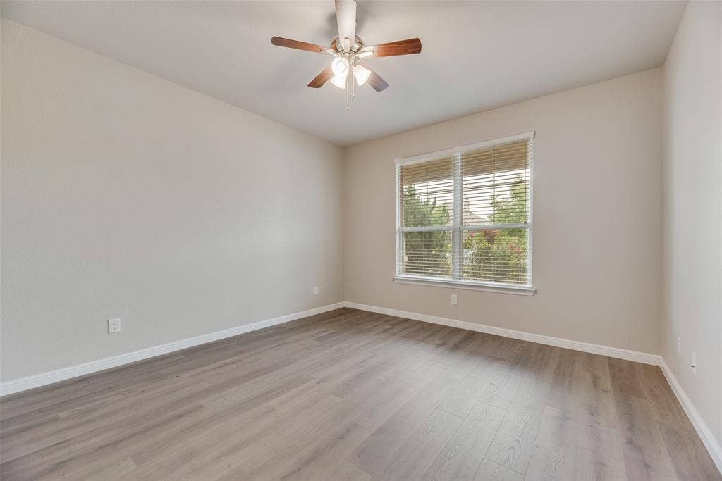 Empty room featuring a ceiling fan and light wood finished floors