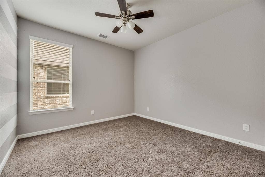 Empty room featuring carpet floors and a ceiling fan