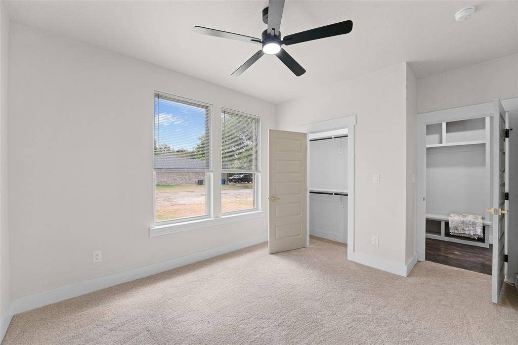 609 Luzon Street, Tool, TX 75143 Carpeted bedroom featuring a contemporary ceiling fan with integrated lighting, two windows, and two closet spaces