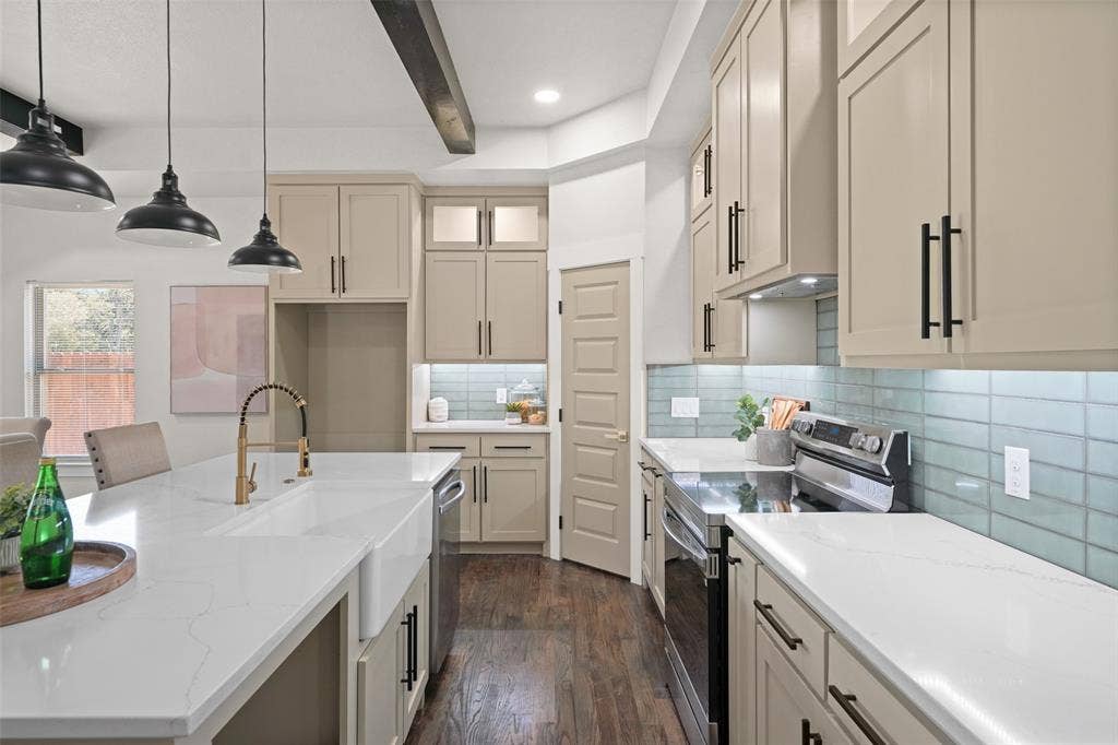 609 Luzon Street, Tool, TX 75143 Gourmet kitchen featuring a large island with an integrated farmhouse sink, quartz countertops, light-toned cabinetry with matte black hardware, and a subway tile backsplash