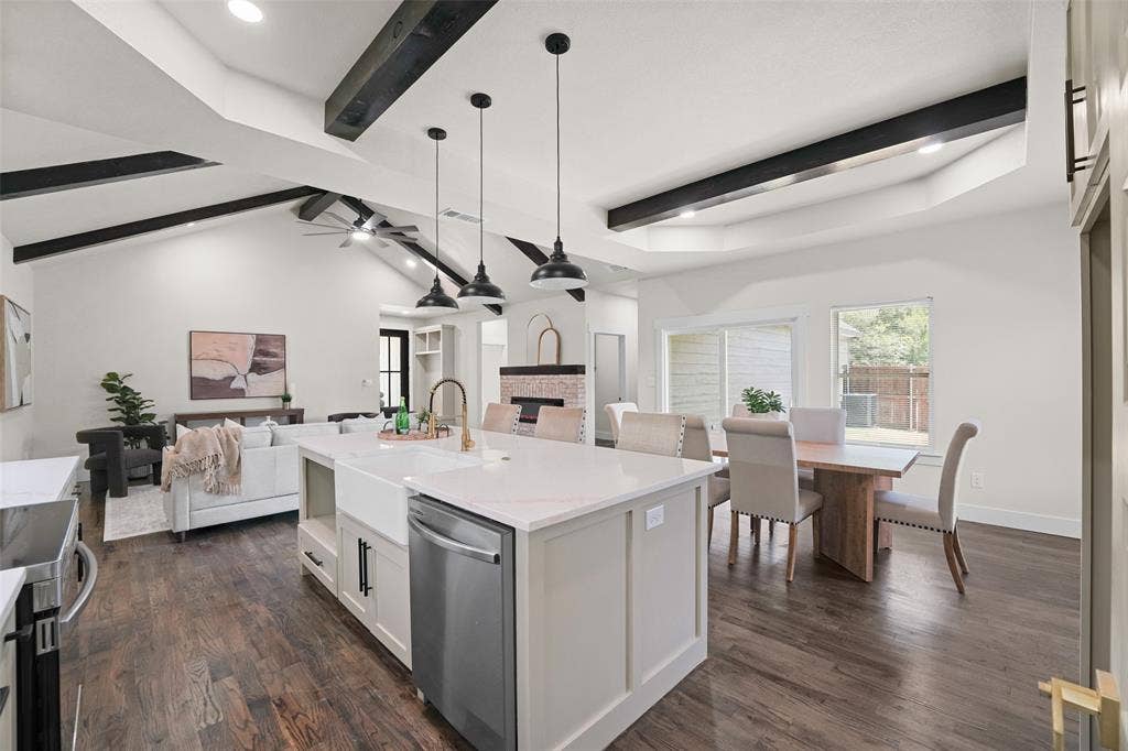 609 Luzon Street, Tool, TX 75143 Open-concept living space featuring wood-finish flooring, a kitchen island with a farmhouse sink and pendant lighting, a vaulted ceiling with exposed beams, and a dining area with direct outdoor access