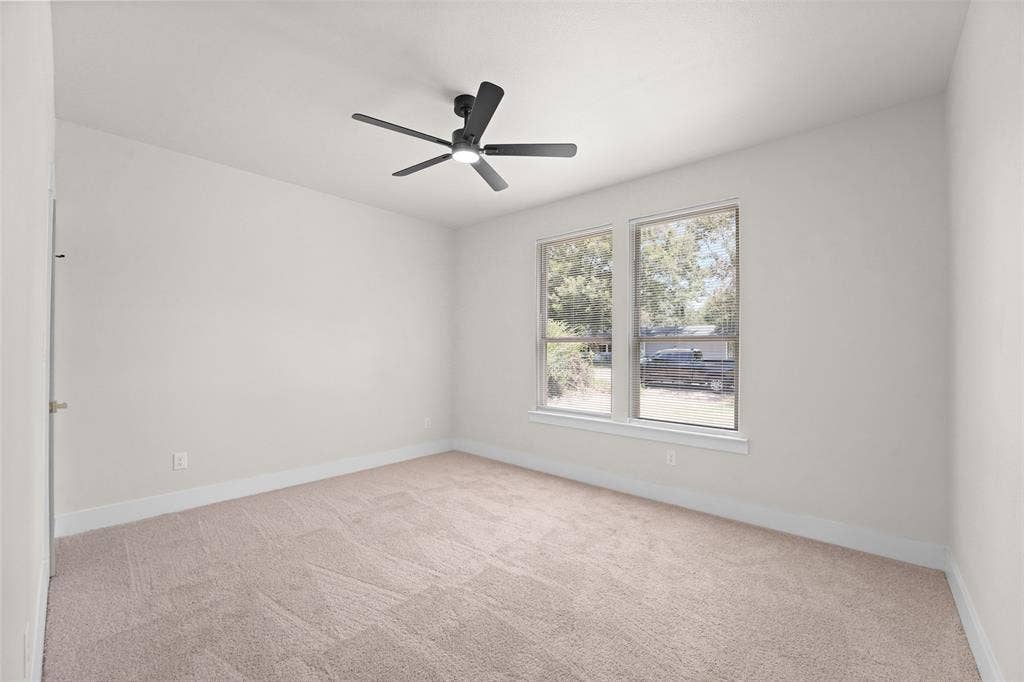 609 Luzon Street, Tool, TX 75143 Bright room featuring two large windows, neutral-toned carpet, a ceiling fan with integrated lighting, and white baseboards