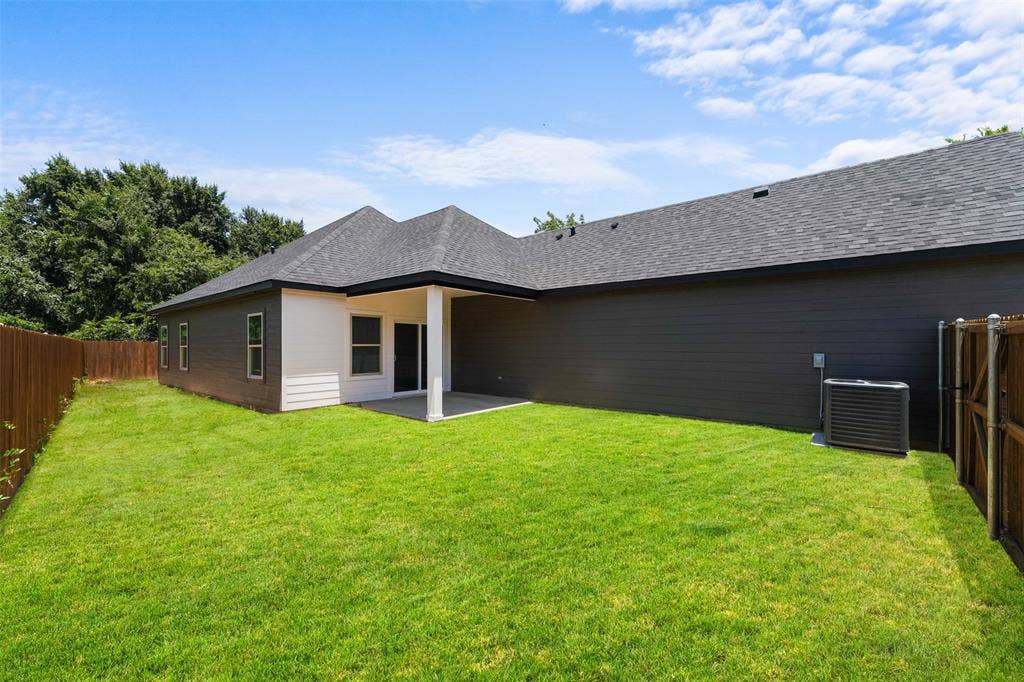 609 Luzon Street, Tool, TX 75143 Expansive green lawn surrounding a modern residence with dark siding and a covered patio