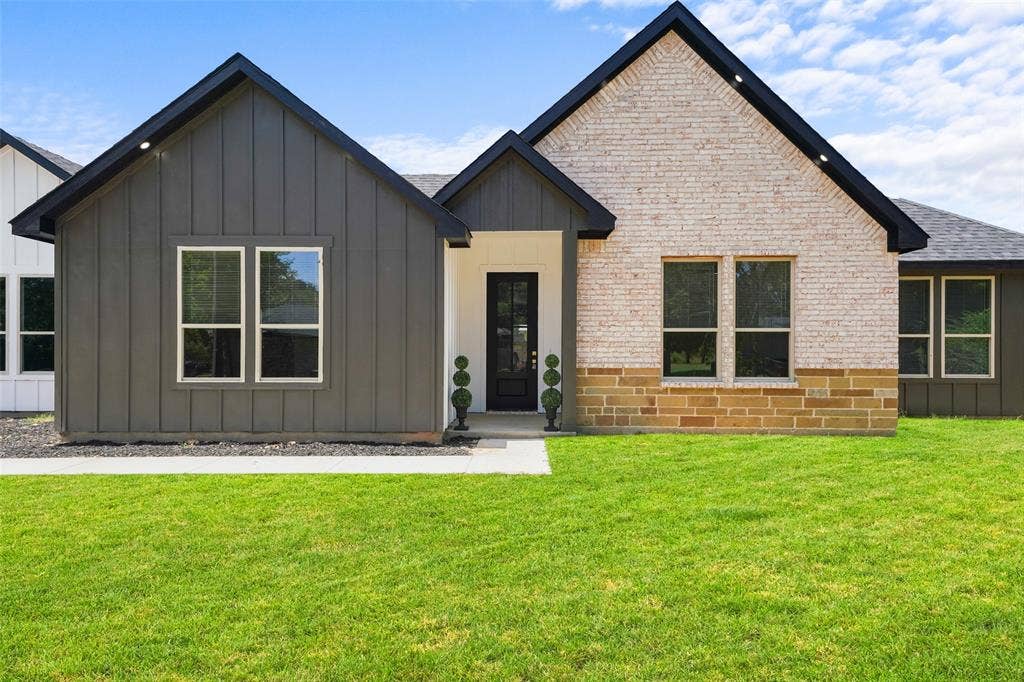 609 Luzon Street, Tool, TX 75143 Contemporary exterior featuring a combination of light-colored brick, vertical dark siding, and a stone accent foundation
