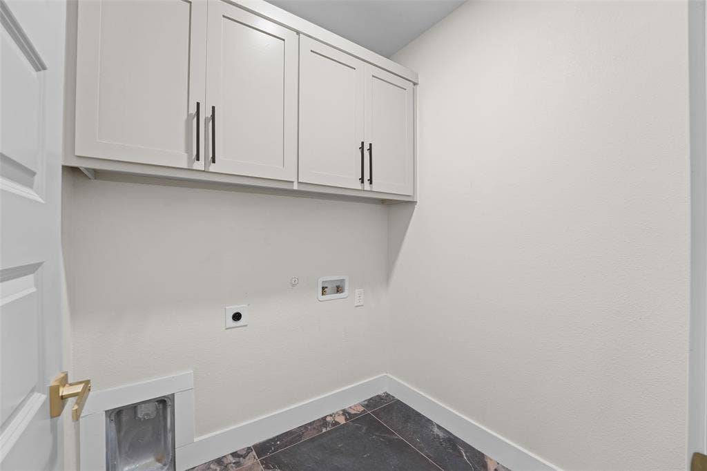 609 Luzon Street, Tool, TX 75143 Utility room featuring white shaker cabinetry with black hardware, dark marble-look tile flooring, and white baseboards