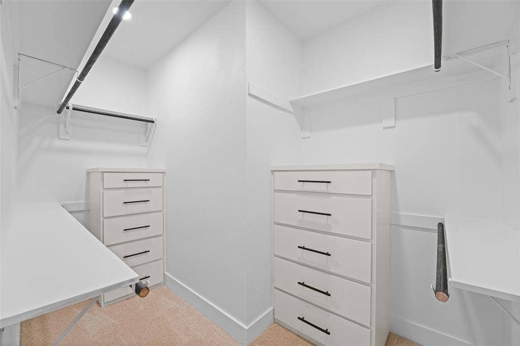 609 Luzon Street, Tool, TX 75143 Walk-in closet featuring white built-in cabinetry with black hardware, track lighting, shelves, and hanging rods