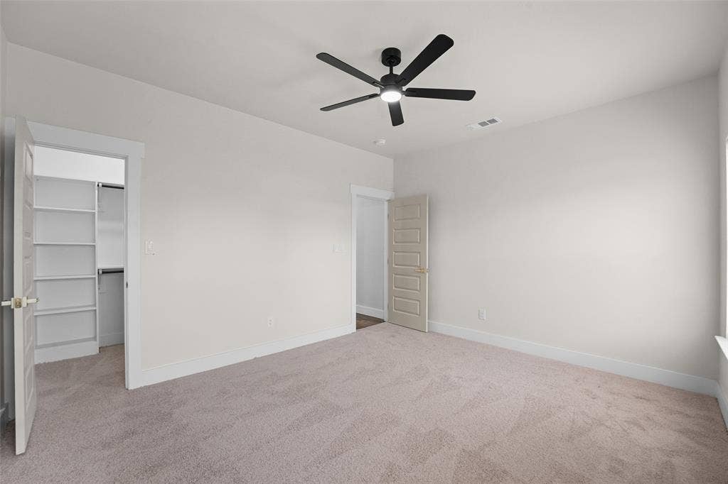 609 Luzon Street, Tool, TX 75143 Spacious room featuring neutral carpeting, a contemporary ceiling fan with integrated lighting, and a walk-in closet with built-in shelving