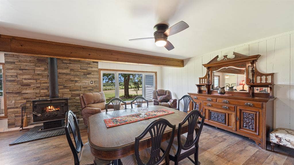 1053 Vz County Road 4206, Athens, TX 75752 Spacious room featuring a stone-clad wood-burning stove, wood-finish flooring, a wood beam, and panoramic windows