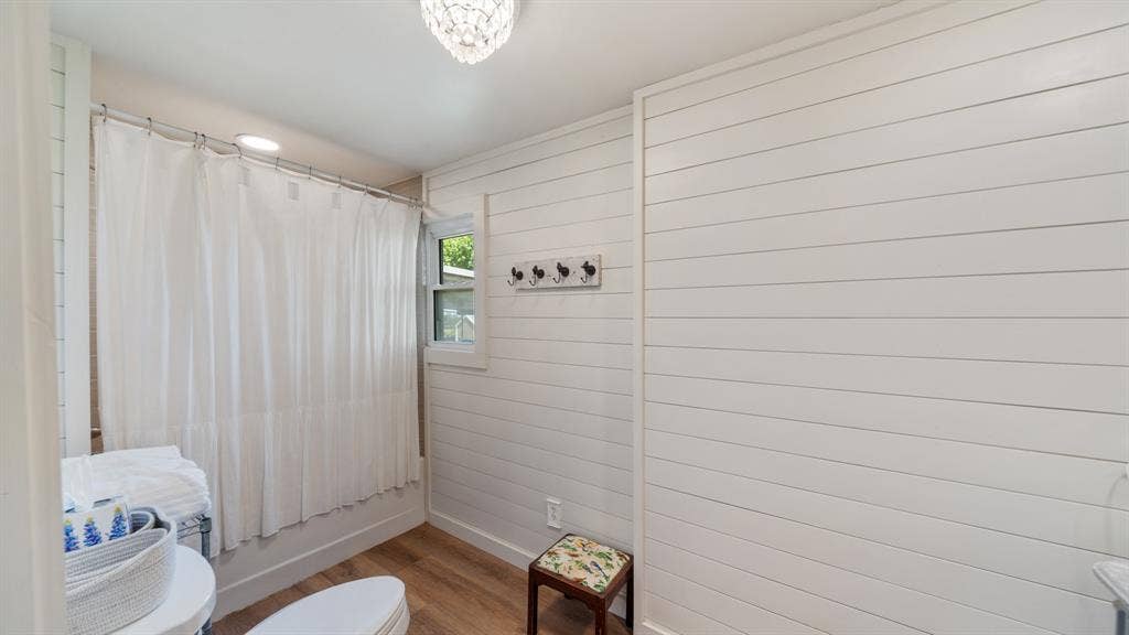 1053 Vz County Road 4206, Athens, TX 75752 Bathroom featuring white shiplap walls, wood-finish flooring, a window, and a built-in shower with a curtain rod