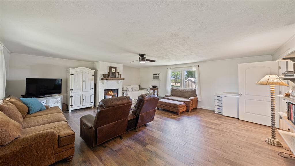 1053 Vz County Road 4206, Athens, TX 75752 Spacious living area featuring wood-finish flooring, a white-painted fireplace with a wood mantle, and a ceiling fan