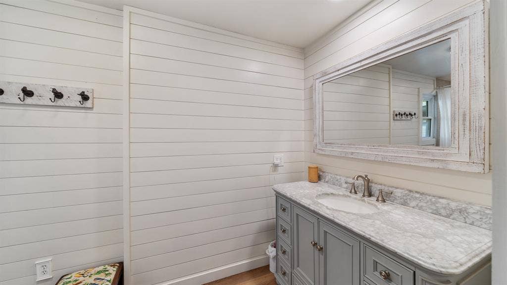 1053 Vz County Road 4206, Athens, TX 75752 Shiplap walls complement a vanity featuring a light gray cabinet, a white oval undermount sink, a marble countertop, and a distressed wood-frame mirror