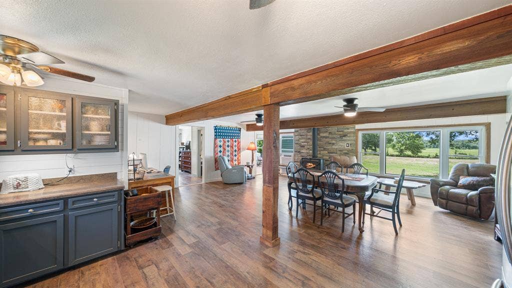 1053 Vz County Road 4206, Athens, TX 75752 Open-concept interior featuring wood-finish flooring, exposed wood beams, and a stone-clad wall with a built-in stove