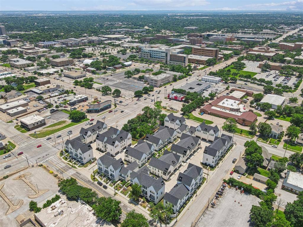 123 Thornton Street, Arlington, TX 76013 Aerial perspective showcasing a collection of residential townhomes with dark roofs and light-colored exteriors, situated within an urban environment