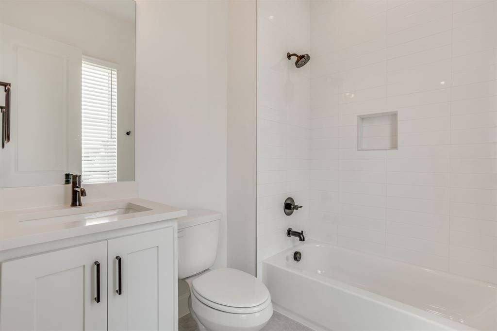 123 Thornton Street, Arlington, TX 76013 Contemporary bathroom featuring a built-in tub with white subway tile surround, integrated shower niche, and matte black fixtures