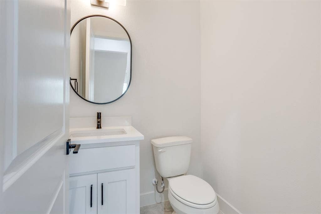 123 Thornton Street, Arlington, TX 76013 White vanity with integrated sink, black faucet, and oval mirror