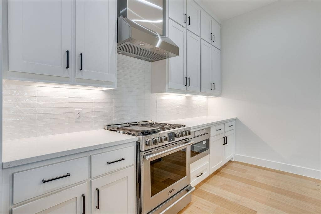 123 Thornton Street, Arlington, TX 76013 Modern kitchen featuring white shaker cabinetry, stainless steel range with matching hood, quartz countertops, and a white subway tile backsplash