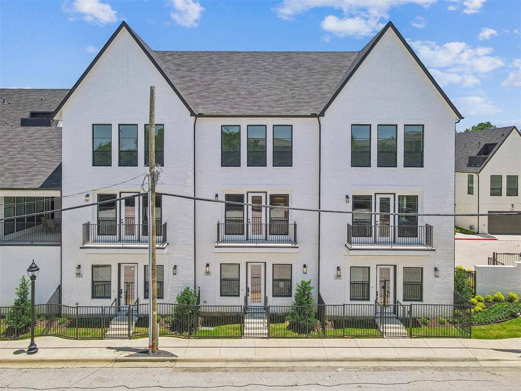 123 Thornton Street, Arlington, TX 76013 Contemporary townhome facade featuring white brick, black-framed windows, steep gables with dark shingle roofing, and individual iron-fenced front patios