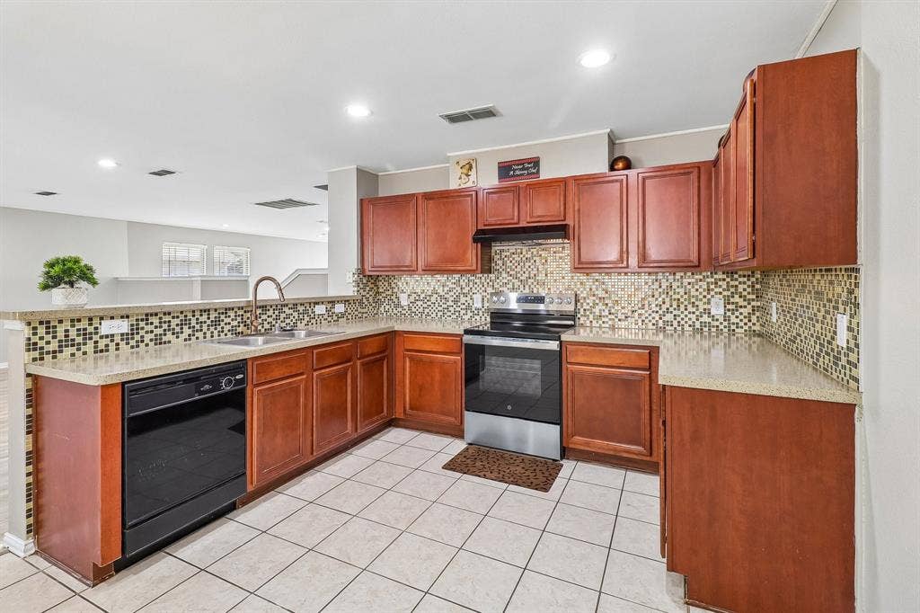 503 Angela Lane, Euless, TX 76039 Kitchen featuring rich wood cabinetry, patterned tile backsplash, and light-toned countertops