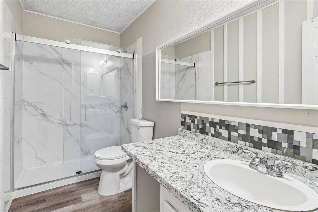 503 Angela Lane, Euless, TX 76039 Bathroom featuring a walk-in shower with clear glass doors and marble-look wall panels