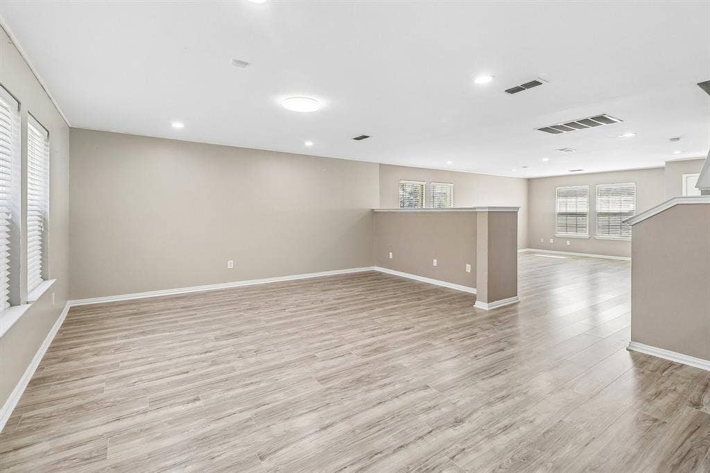 503 Angela Lane, Euless, TX 76039 Expansive open-concept room featuring light wood-finish flooring, recessed lighting, multiple windows with blinds, and neutral wall paint