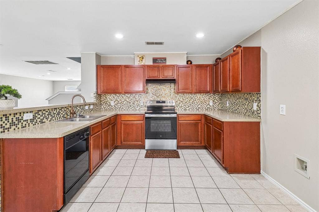 503 Angela Lane, Euless, TX 76039 U-shaped kitchen featuring wood cabinetry, stone-finish countertops, and a mosaic tile backsplash