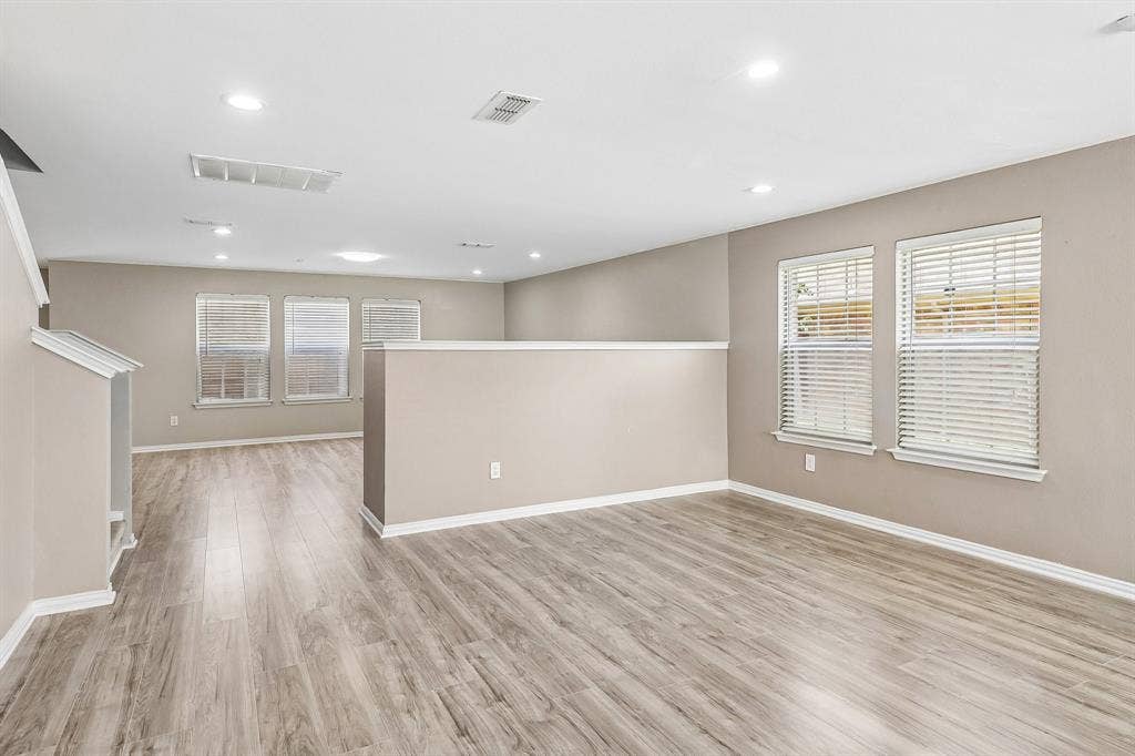 503 Angela Lane, Euless, TX 76039 Spacious room featuring wood-finish flooring, multiple windows, recessed lighting, and neutral wall tones