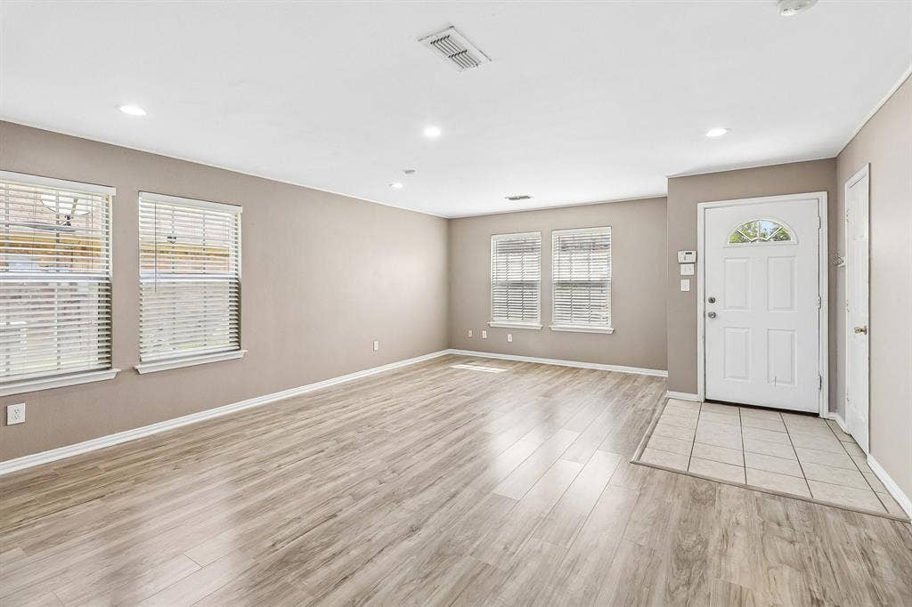 503 Angela Lane, Euless, TX 76039 Spacious room featuring wood-finish flooring, neutral-toned walls, recessed lighting, and multiple windows with blinds