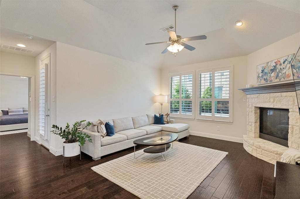 Living area featuring dark wood-finish flooring and a white stone-clad fireplace