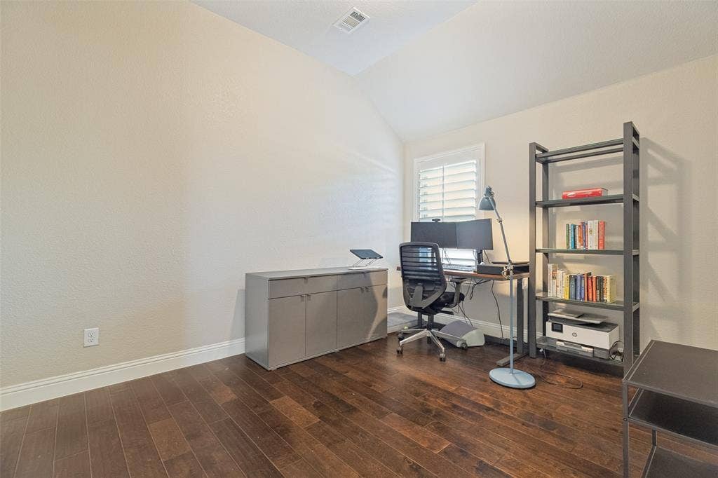 Hardwood-finish flooring throughout, featuring a vaulted ceiling and a window with plantation shutters