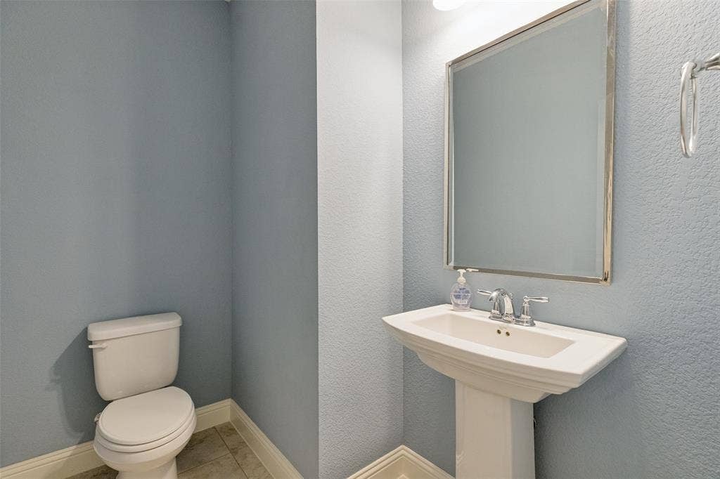Pedestal sink with chrome faucet, mirrored vanity, and tiled flooring