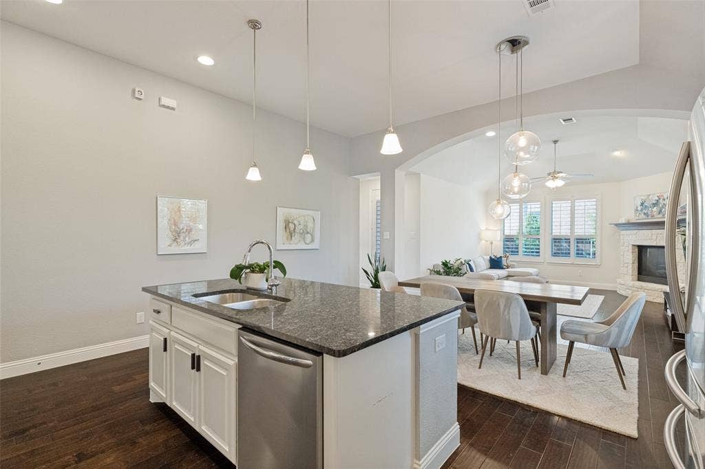 Modern kitchen island featuring a stainless steel sink, granite countertop, and integrated dishwasher
