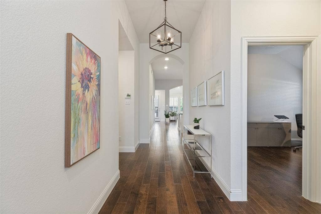 Expansive hallway featuring wood-finish flooring, an arched entryway, and a geometric pendant light fixture