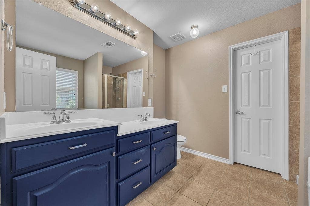 1201 Destiny Court, Wylie, TX 75098 Dual vanity with integrated sinks, ample cabinet storage, a large wall-mounted mirror, overhead vanity lighting, and tile flooring