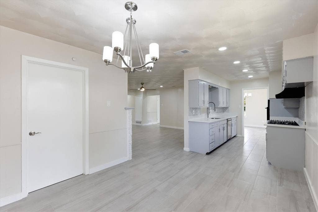 3301 Hillsdale Lane, Garland, TX 75042 Open-concept living space featuring wood-finish flooring, a contemporary chandelier, recessed lighting, light-toned walls, and a modern kitchen with grey cabinetry and stainless steel appliances