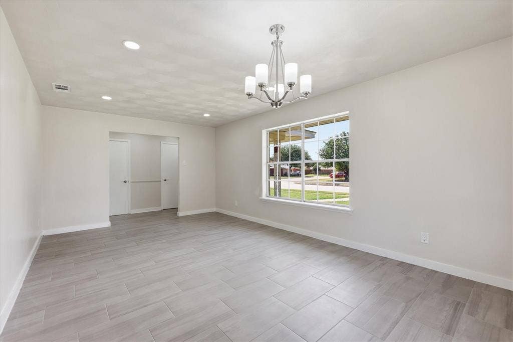 3301 Hillsdale Lane, Garland, TX 75042 Spacious room featuring light gray walls, large front-facing window, recessed lighting, and a chrome chandelier with five frosted glass shades