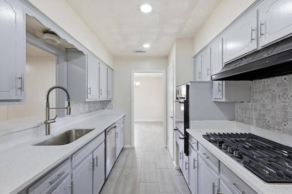 3301 Hillsdale Lane, Garland, TX 75042 Galley kitchen featuring light gray cabinetry, light-toned countertops, and a decorative tile backsplash