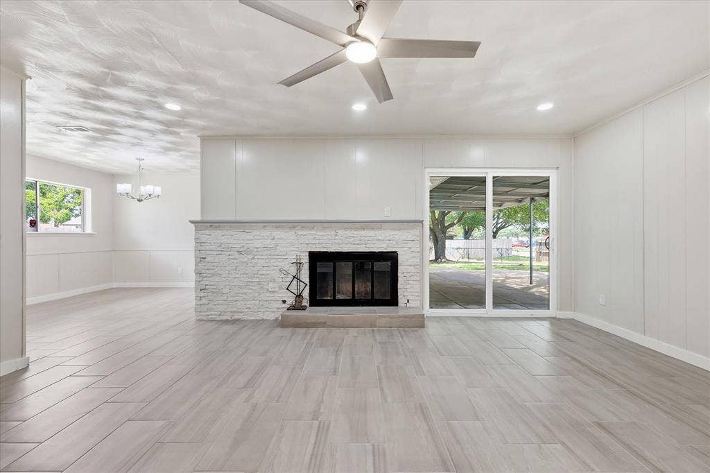 3301 Hillsdale Lane, Garland, TX 75042 Spacious living area featuring wood-look tile flooring, a white brick fireplace with a stone mantel, recessed lighting, and a ceiling fan