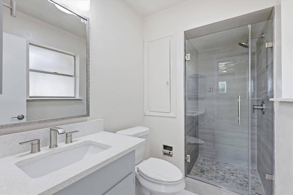 3301 Hillsdale Lane, Garland, TX 75042 Bathroom featuring a walk-in shower with glass enclosure, pebble stone shower floor, and gray subway tile surround